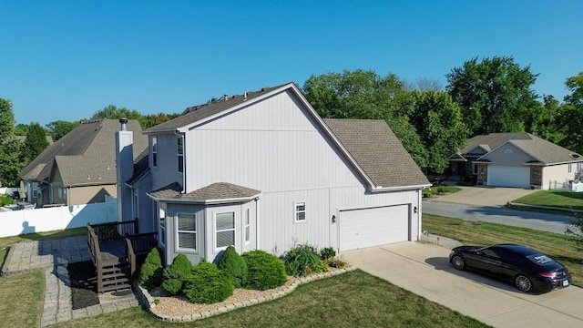 view of home's exterior with a yard, a shingled roof, fence, a garage, and driveway