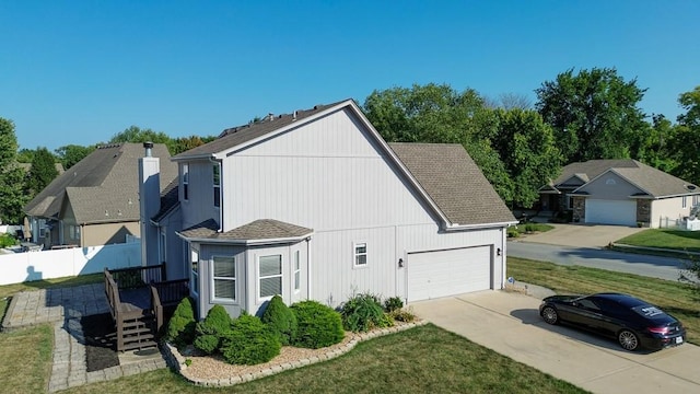 view of side of home with a yard, a shingled roof, and fence