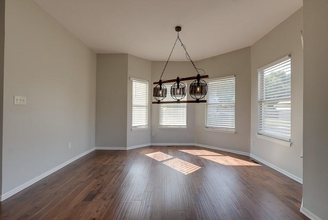 unfurnished dining area with dark wood-style floors, plenty of natural light, and baseboards