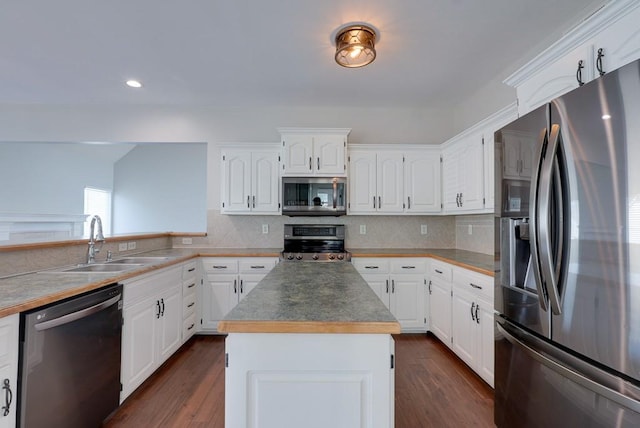 kitchen with tasteful backsplash, appliances with stainless steel finishes, white cabinetry, a kitchen island, and a sink