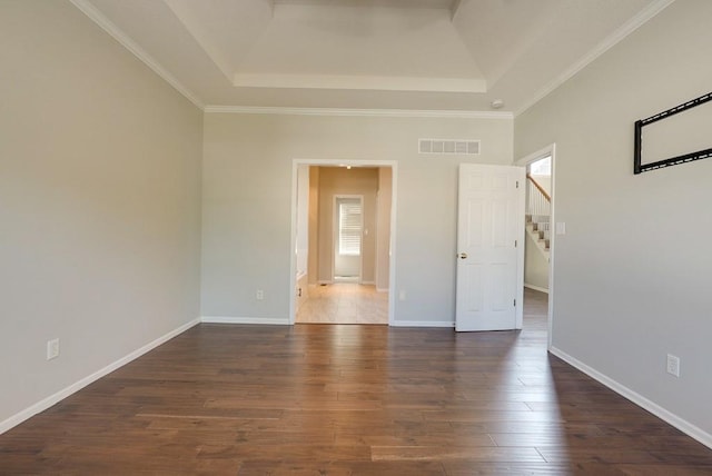 empty room featuring a tray ceiling, baseboards, visible vents, and dark wood-type flooring