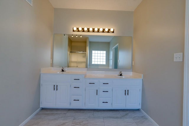 bathroom with marble finish floor, double vanity, a stall shower, and a sink