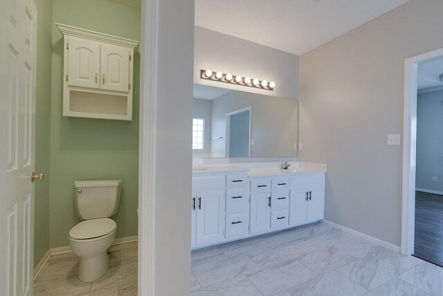 full bathroom with marble finish floor, baseboards, a sink, and toilet