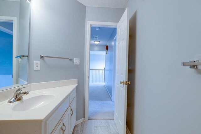 bathroom with a textured ceiling, vanity, and baseboards