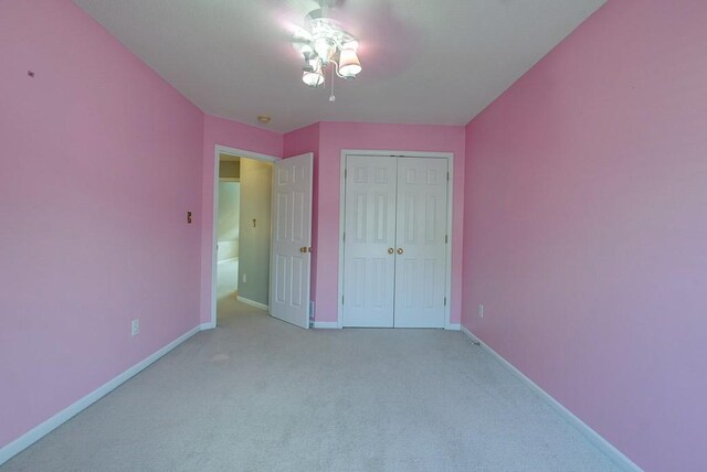 unfurnished bedroom featuring light carpet, baseboards, and a closet