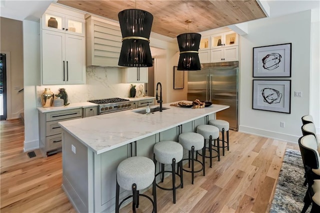 2207 W 71st St, Prairie Village, KS 66208 - kitchen featuring premium appliances, wooden ceiling, a sink, light wood finished floors, and a kitchen island with sink