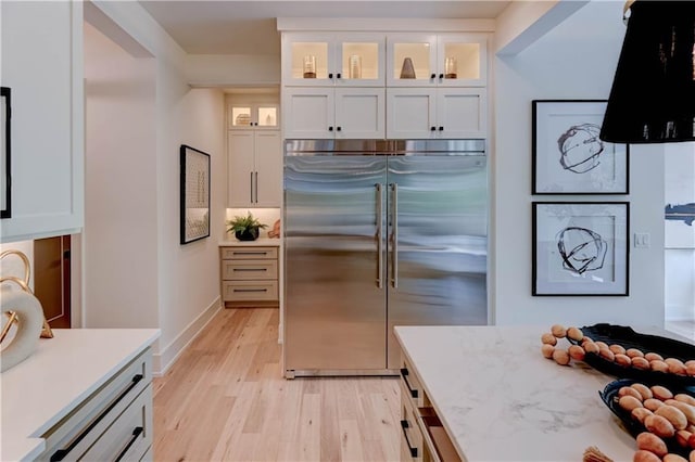2207 W 71st St, Prairie Village, KS 66208 - kitchen featuring stainless steel built in fridge, light wood-style floors, white cabinetry, light countertops, and glass insert cabinets