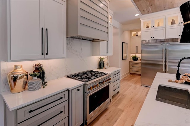 2207 W 71st St, Prairie Village, KS 66208 - kitchen with high end appliances, custom range hood, a sink, light countertops, and backsplash