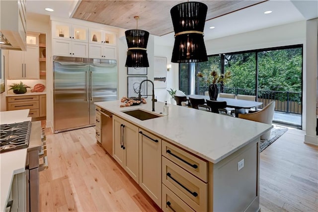 2207 W 71st St, Prairie Village, KS 66208 - kitchen featuring appliances with stainless steel finishes, a sink, exhaust hood, light wood-style flooring, and pendant lighting