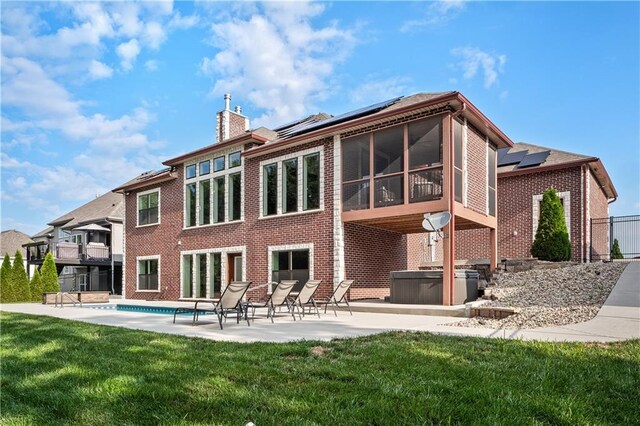 rear view of property with a balcony, a lawn, a patio, solar panels, and a sunroom