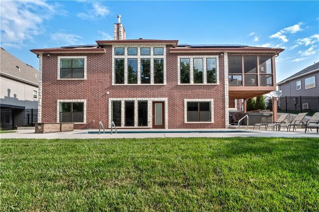 rear view of property featuring a lawn, a patio, and a sunroom