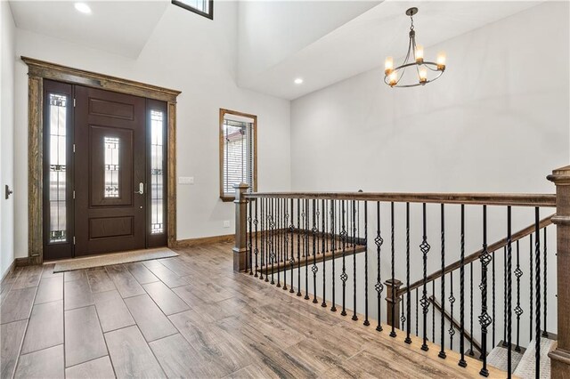 entrance foyer with wood-type flooring, a notable chandelier, and vaulted ceiling