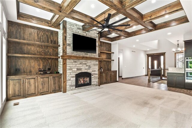 carpeted living room featuring coffered ceiling, ceiling fan with notable chandelier, wooden walls, and a fireplace