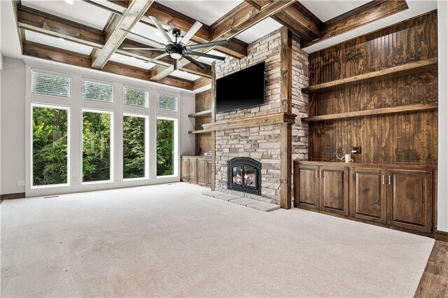 unfurnished living room featuring a fireplace, carpet flooring, beamed ceiling, coffered ceiling, and ceiling fan