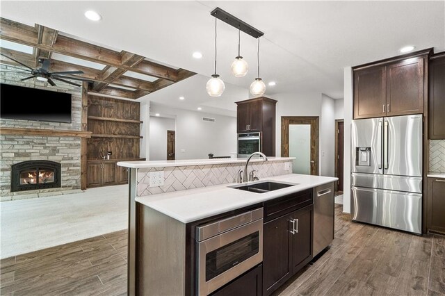 kitchen with a fireplace, hardwood / wood-style floors, stainless steel appliances, sink, and ceiling fan