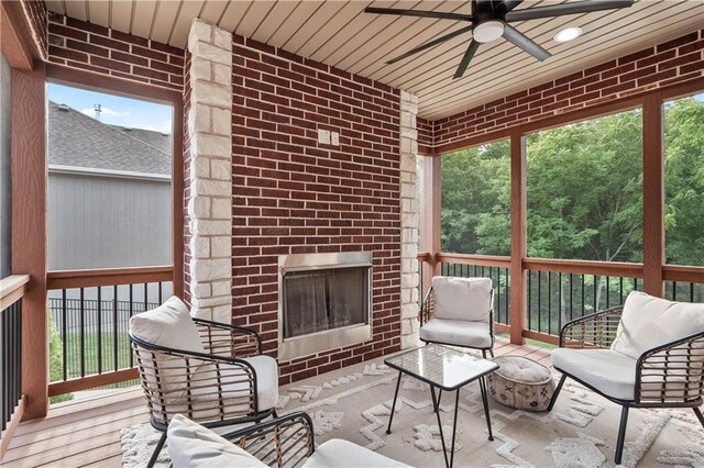 sunroom / solarium featuring plenty of natural light, ceiling fan, and a fireplace