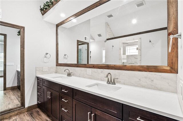 bathroom featuring hardwood / wood-style floors, vaulted ceiling, tasteful backsplash, and vanity