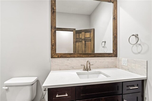 bathroom with vanity, toilet, and decorative backsplash