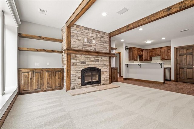 unfurnished living room featuring carpet floors and a stone fireplace