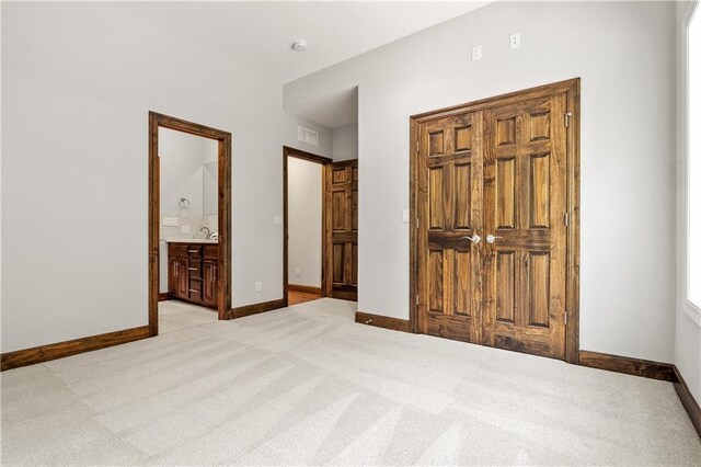 unfurnished bedroom featuring connected bathroom and light colored carpet