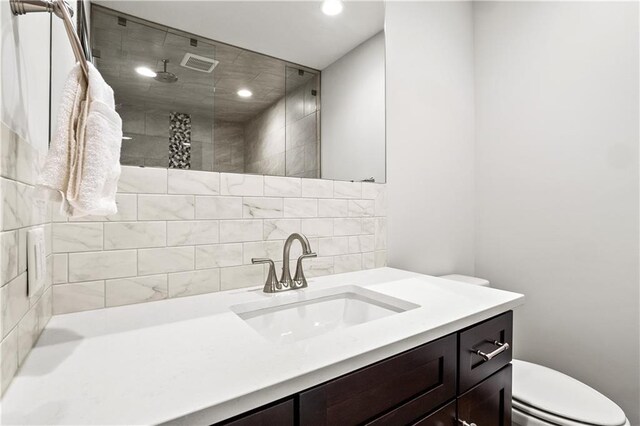 bathroom featuring vanity, toilet, and tiled shower