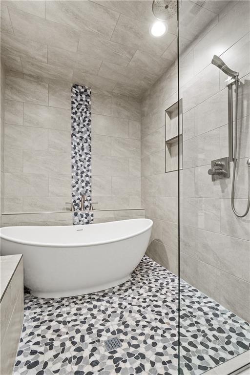 bathroom with tile patterned flooring, tile walls, and plus walk in shower