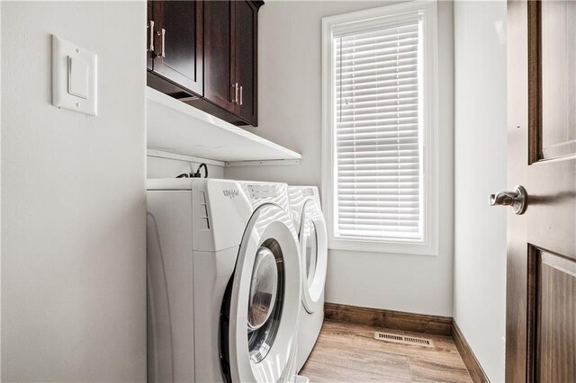 laundry room with cabinets, washer and dryer, and light hardwood / wood-style floors