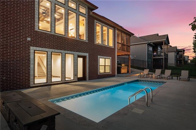 pool at dusk featuring a patio