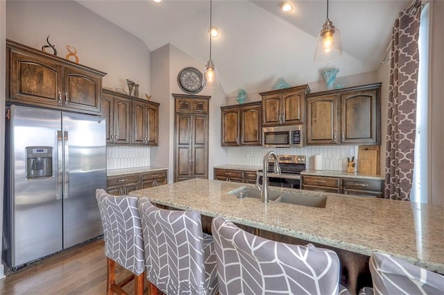 kitchen featuring hanging light fixtures, backsplash, hardwood / wood-style floors, and stainless steel appliances