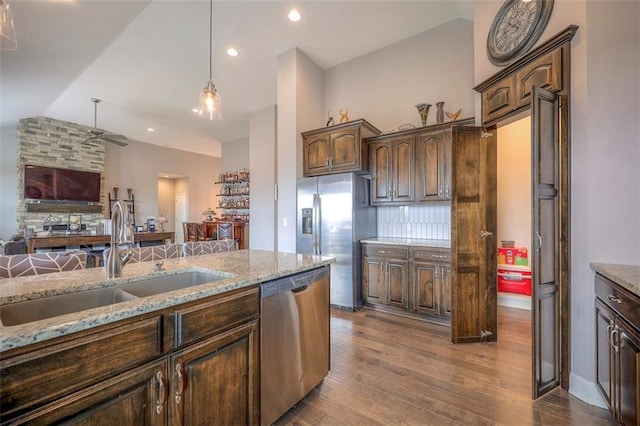 kitchen with tasteful backsplash, hardwood / wood-style floors, appliances with stainless steel finishes, light stone counters, and sink