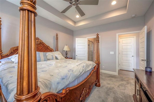 bedroom featuring ceiling fan, light colored carpet, and a tray ceiling