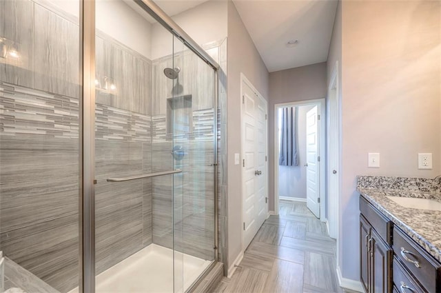 bathroom featuring a shower with door and vanity