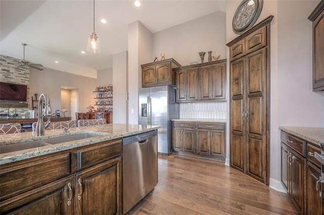 kitchen with appliances with stainless steel finishes, decorative backsplash, light stone counters, wood-type flooring, and ceiling fan