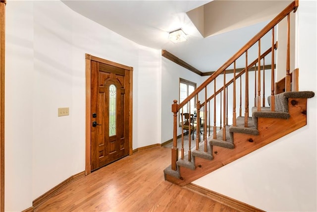 entryway with ornamental molding and light wood-type flooring