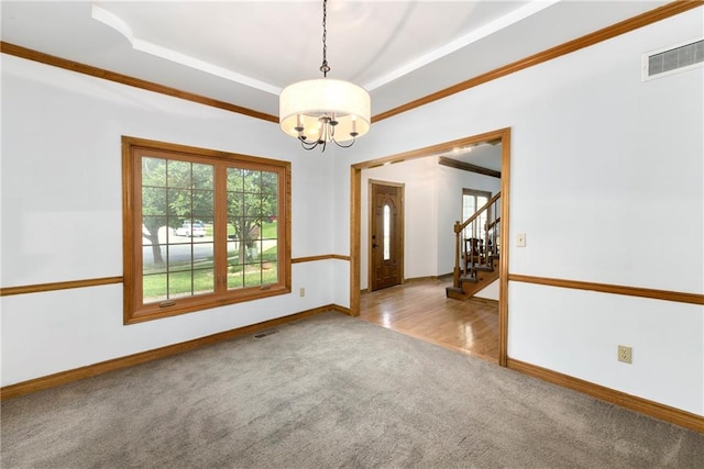 spare room featuring ornamental molding, a chandelier, and carpet