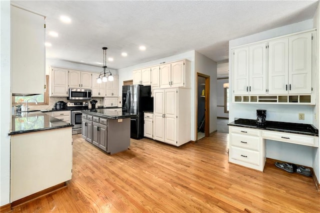 kitchen featuring white cabinetry, light wood-type flooring, stainless steel appliances, pendant lighting, and a center island