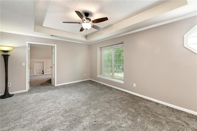 unfurnished bedroom featuring ceiling fan, a textured ceiling, a tray ceiling, ornamental molding, and carpet floors