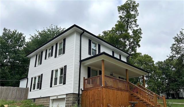 view of property exterior featuring a porch, an attached garage, stairs, and fence