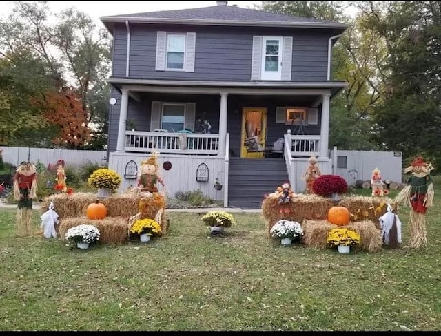 traditional style home with a porch, a front yard, and fence