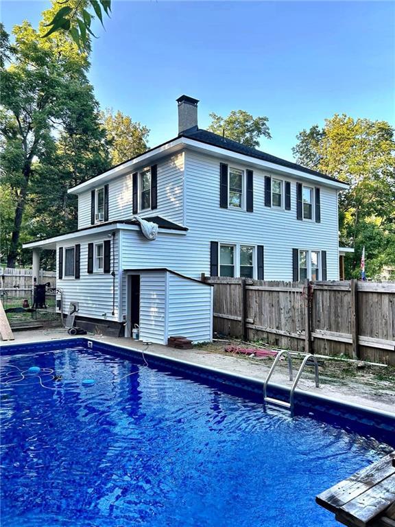 back of house featuring a fenced in pool, a chimney, and fence