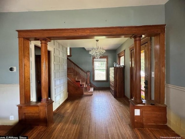 interior space featuring stairs, a notable chandelier, decorative columns, and wood finished floors