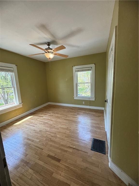 unfurnished room with visible vents, wood-type flooring, and plenty of natural light