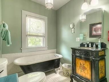 bathroom with a freestanding tub, toilet, an inviting chandelier, and vanity