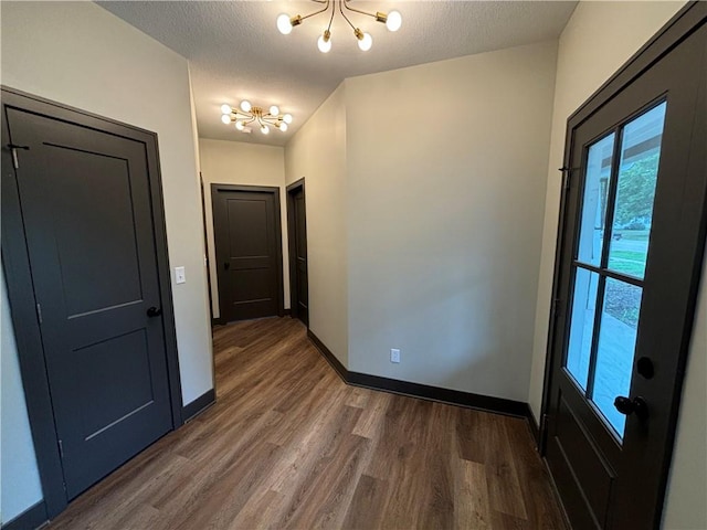 interior space with an inviting chandelier, a textured ceiling, and dark hardwood / wood-style flooring