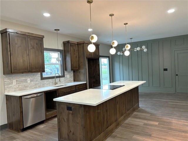 kitchen featuring decorative backsplash, wood-type flooring, decorative light fixtures, stainless steel dishwasher, and sink