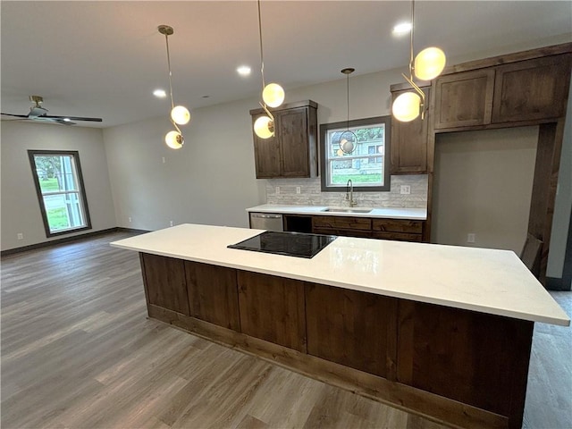 kitchen featuring ceiling fan, hanging light fixtures, sink, hardwood / wood-style flooring, and decorative backsplash