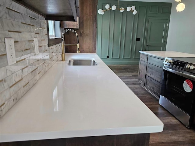 kitchen featuring stainless steel range with electric stovetop, sink, dark wood-type flooring, and green cabinets