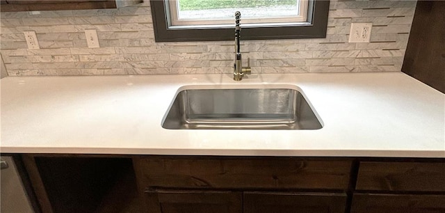 details featuring backsplash, dark brown cabinets, and sink