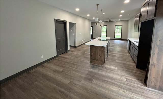 kitchen featuring hanging light fixtures, a kitchen island, dark hardwood / wood-style floors, and dark brown cabinetry