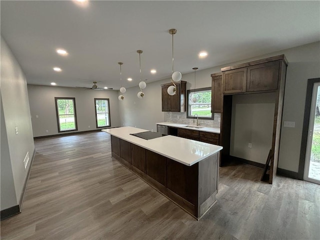 kitchen featuring hardwood / wood-style flooring, a kitchen island, decorative backsplash, decorative light fixtures, and ceiling fan